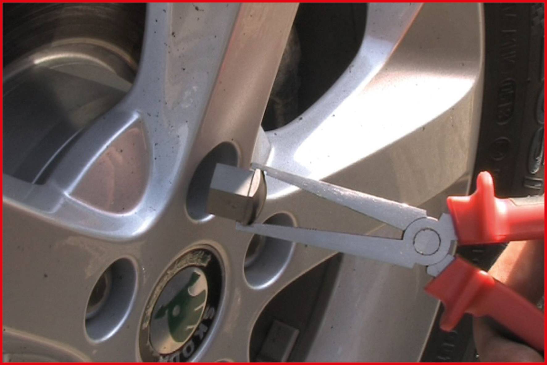 Eine Zange wird zum Entfernen einer Radmutterkappe an einem Autoreifen verwendet.