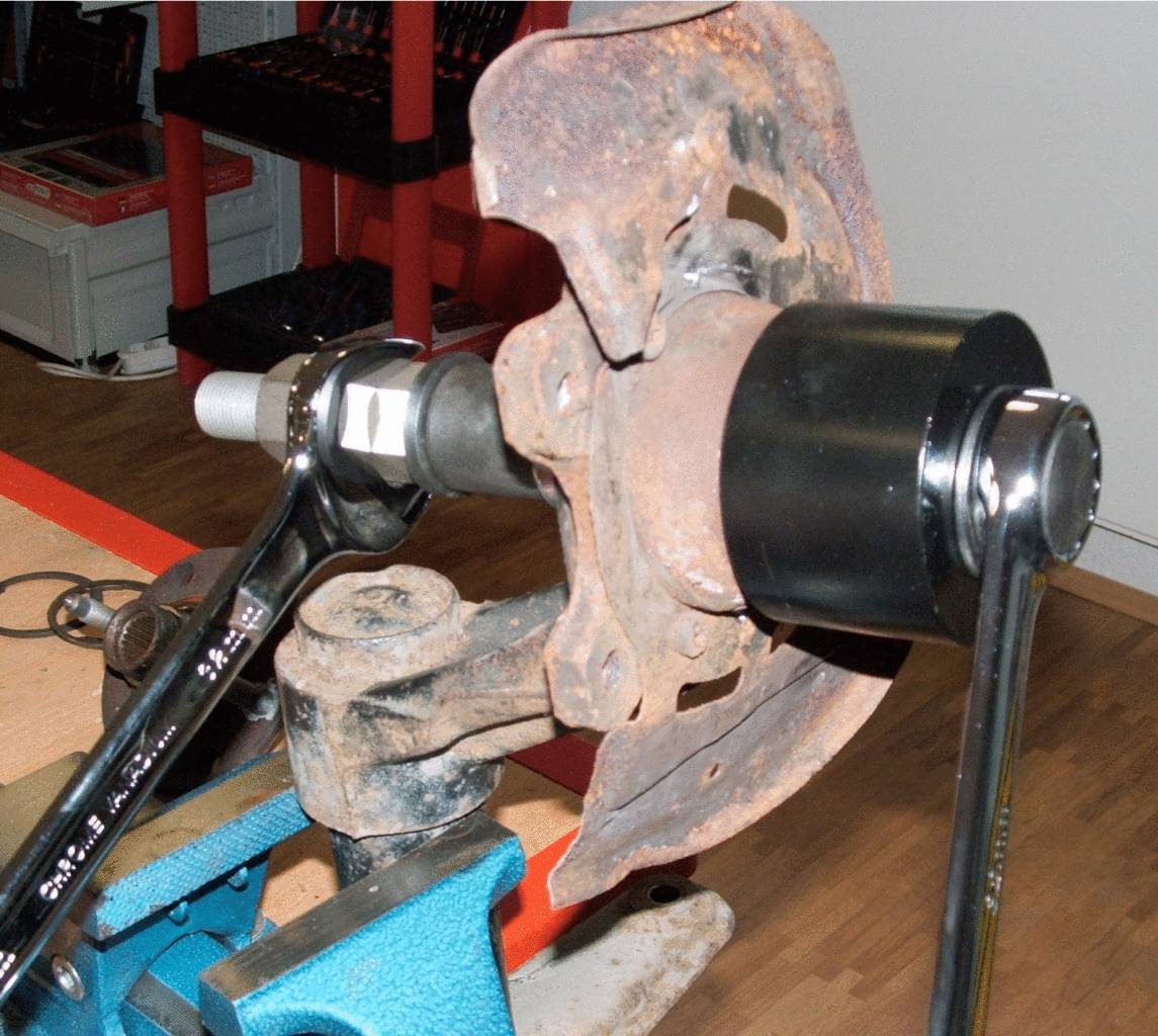 Werkzeugmechanismus, der an einer rostigen Metallscheibe arbeitet, eingespannt in einer Werkbank, umgeben von Werkstattausrüstung.