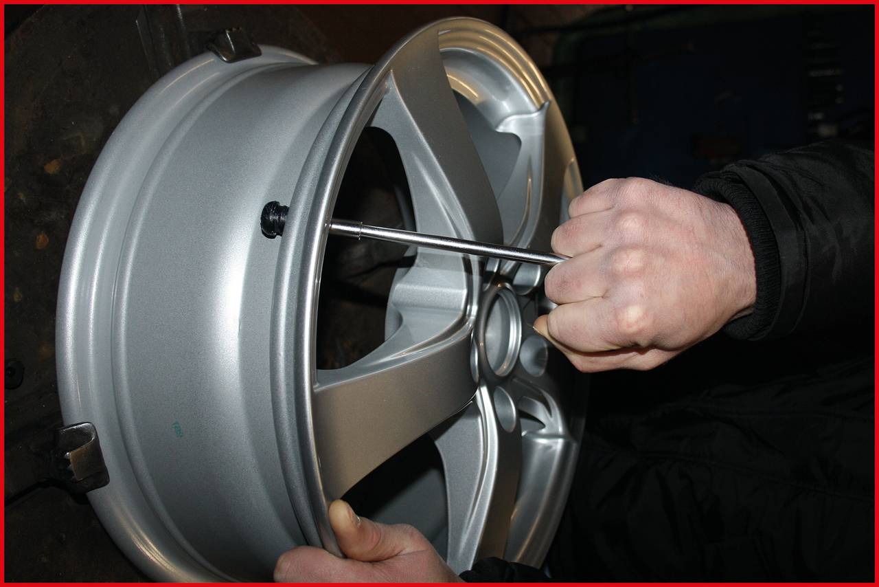 Person montiert eine silberne Felge mit einem Schraubenschlüssel.