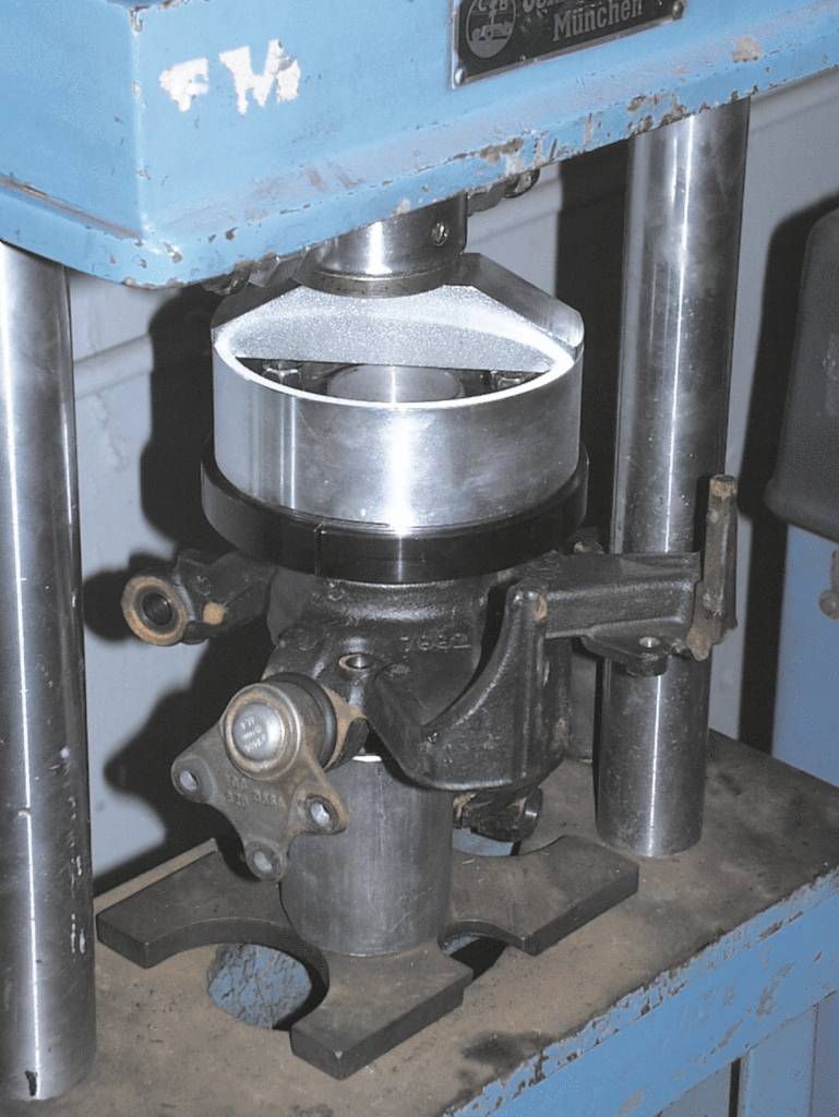 Maschine zur Bearbeitung eines zylindrischen Metallteils, das zwischen vertikalen Stützen eingespannt ist. Umgebung industrieller Werkstatt.