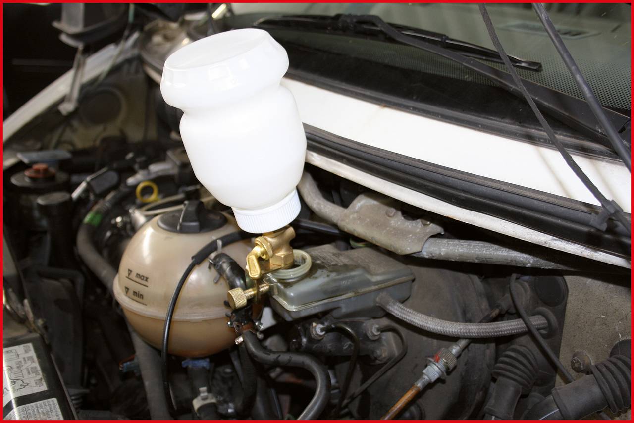 Ein Bremsenentlüftungsgerät ist an einem Auto angebracht. Es steht auf dem Bremsflüssigkeitsbehälter im Motorraum.