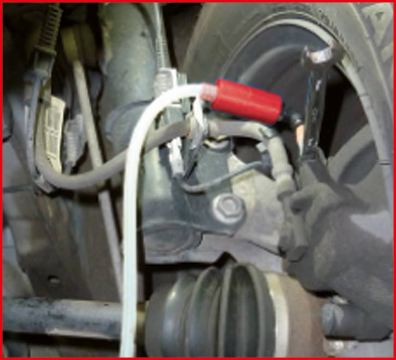 Ein Schraubenschlüssel und Kabel sind an einer Fahrzeugkomponente befestigt. Die Szene zeigt einen Teil eines Reparaturvorgangs.