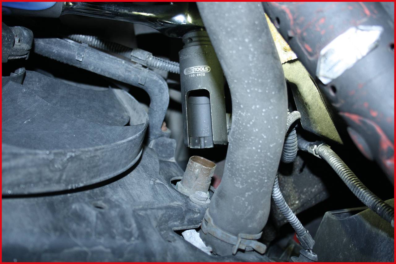 Detailaufnahme eines Fahrzeugmotors mit Fokus auf einen Zündkerzenstecker und umliegende Kabel. Innenansicht eines Motorraums.