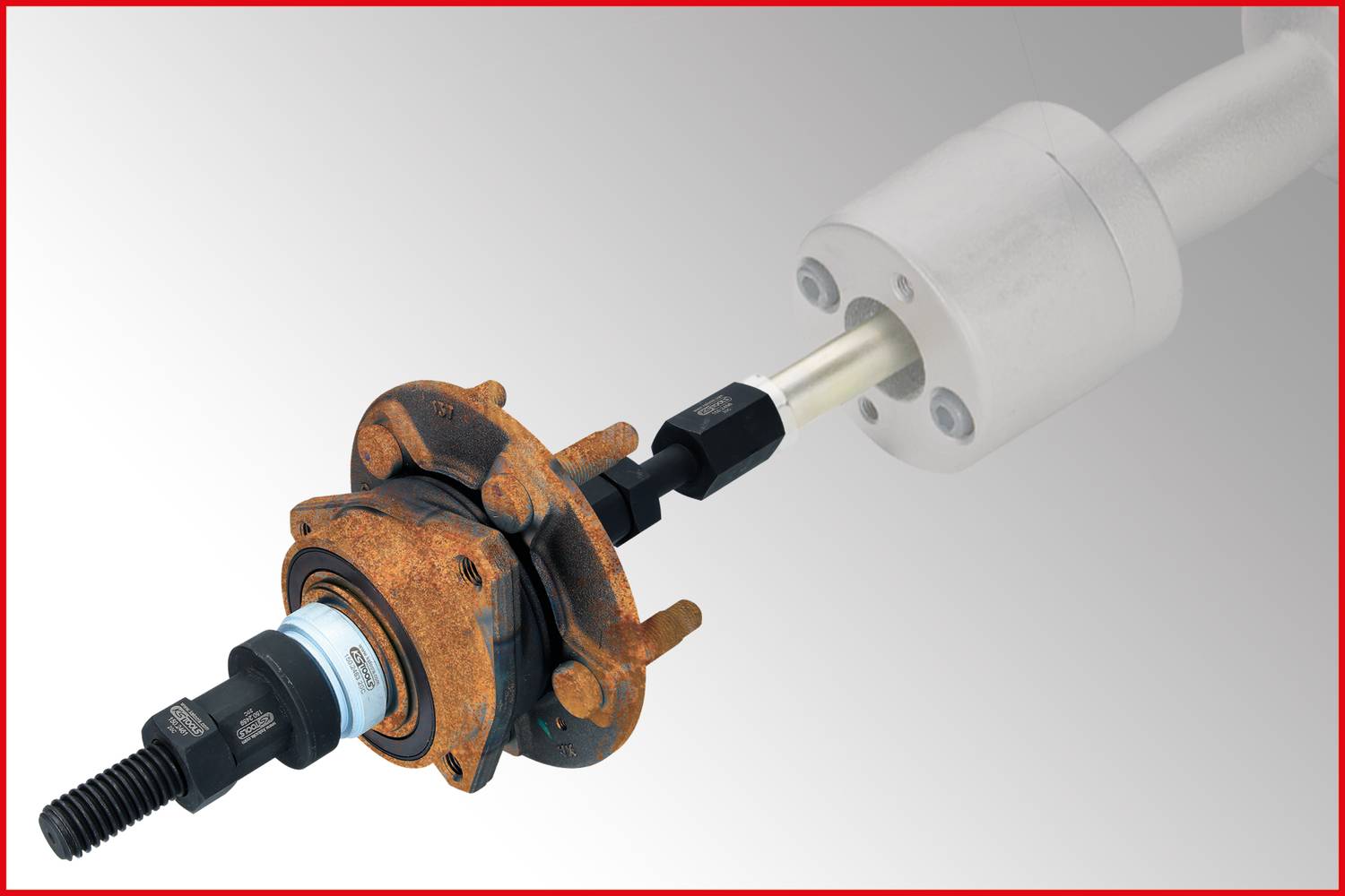 Ein Werkzeug wird in einen verrosteten Radnabenlagersatz eingeführt, um das Lager aus der Nabe zu ziehen, auf grauem Hintergrund.