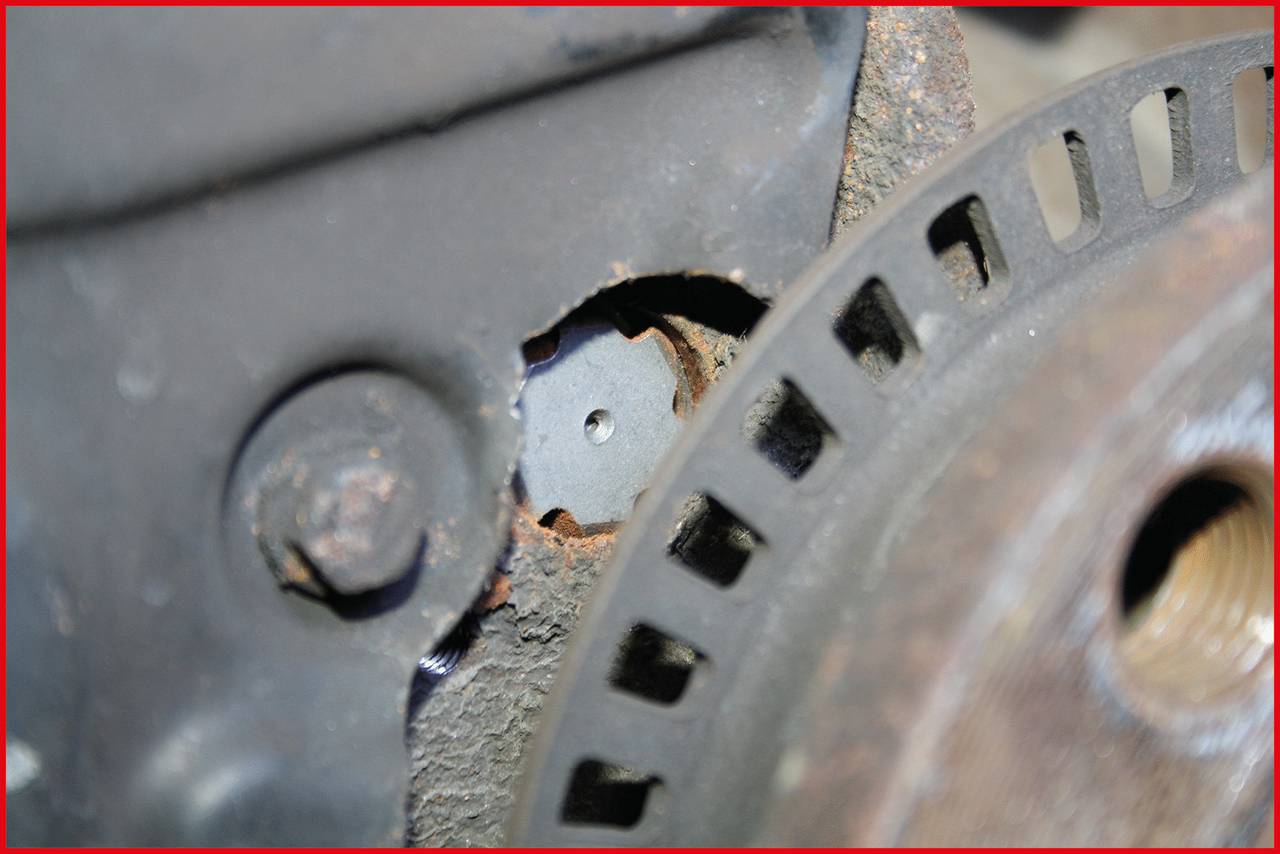 Nahaufnahme einer rostigen mechanischen Komponente, möglicherweise Teil eines Motors. Ein kleines, rundes Bauteil ist in der Mitte sichtbar.