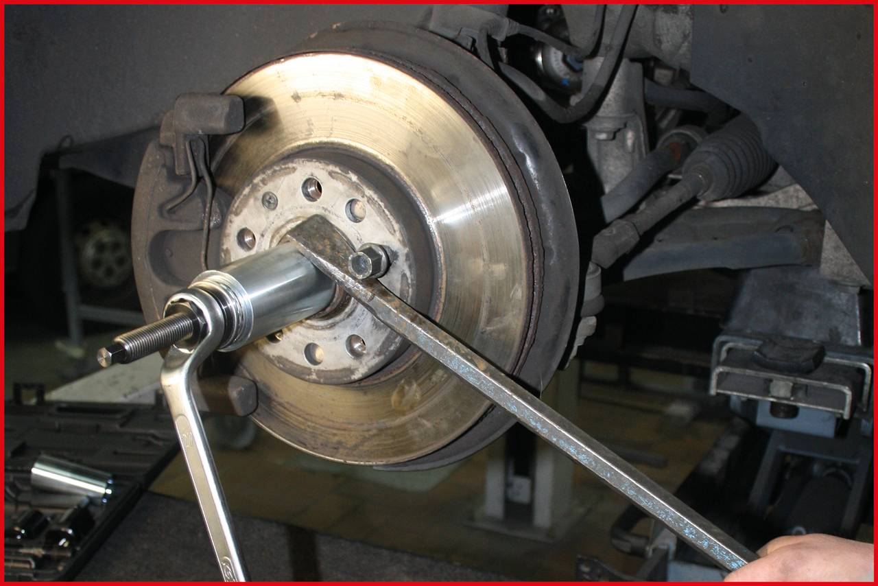 Ein Mechaniker montiert eine Bremsscheibe an einem Auto. Zu sehen sind Bremskomponenten und mechanisches Werkzeug für die Reparatur.