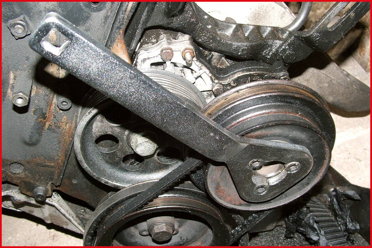 Automotor mit verrosteten Riemenscheiben und einem aufgesetzten Schraubenschlüssel, der zur Reparatur oder Wartung verwendet wird.
