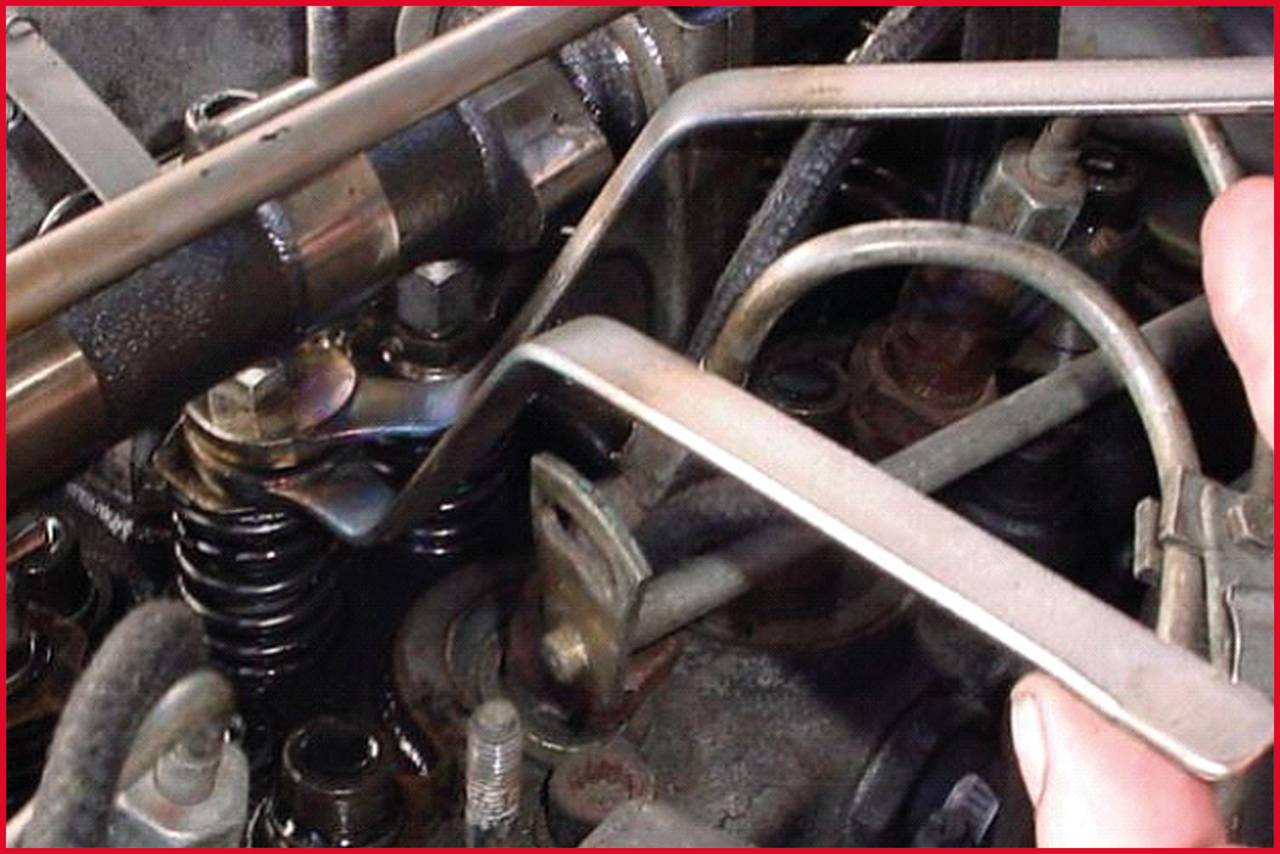 Person justiert die Ventile eines Motors mit einem Schraubenschlüssel. Im Bild sind Ventilfedern und weitere Motorteile zu sehen.