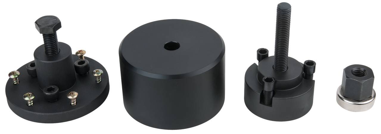 Vier schwarze Metallwerkzeuge in verschiedenen Formen, darunter ein rundes Stück mit Schrauben, ein zylindrisches Teil und zwei weitere Schraubenwerkzeuge.