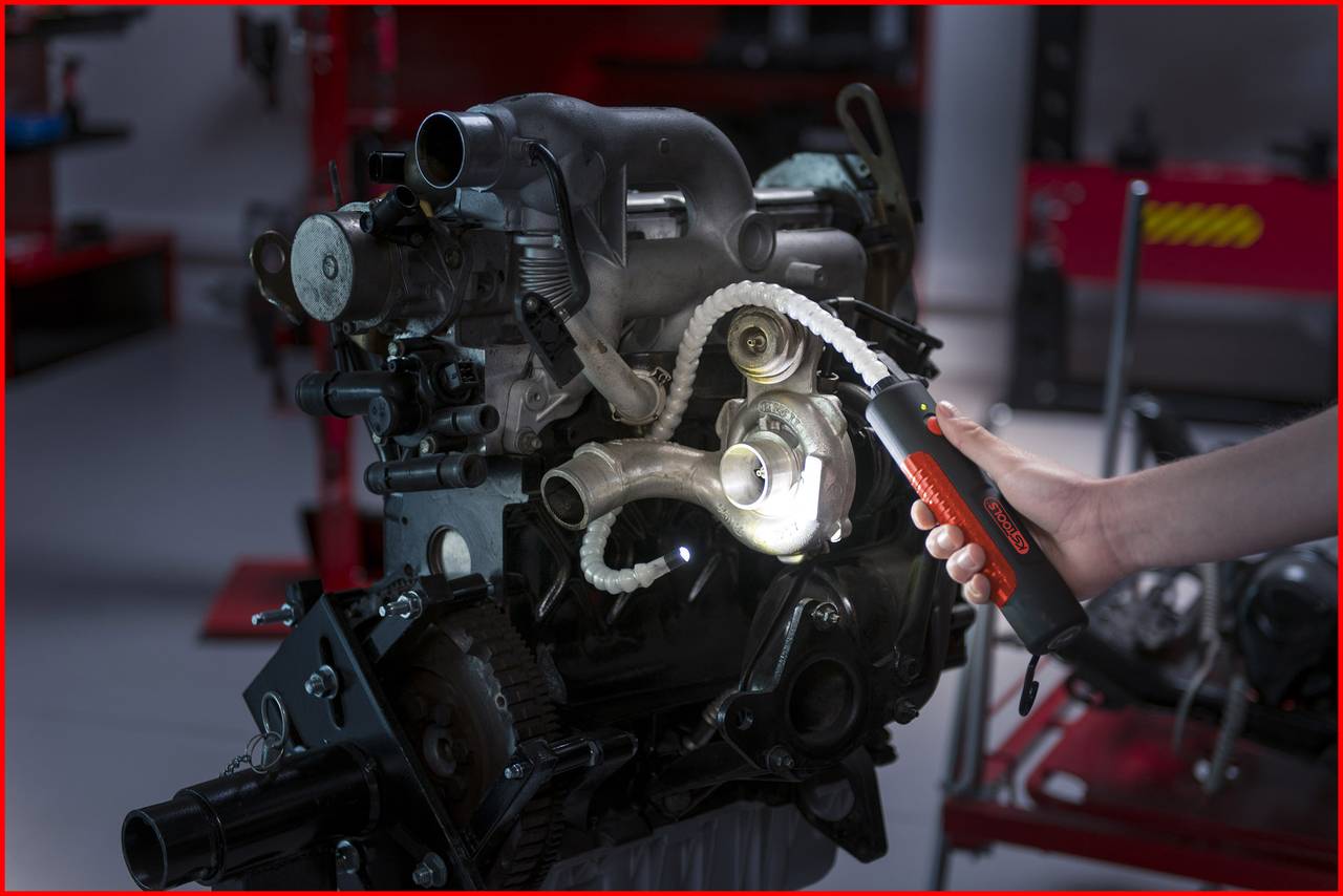 Ein technisches Gerät, dessen Teile mit einer Lampe ausgeleuchtet werden. Eine Person hält die Lampe, um Details sichtbar zu machen.