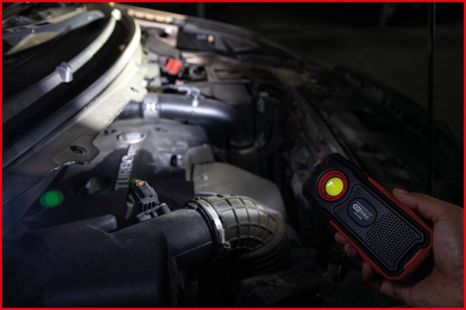 Eine Person leuchtet mit einer tragbaren Lampe in den Motorraum eines Autos, um Details des Motors zu überprüfen.