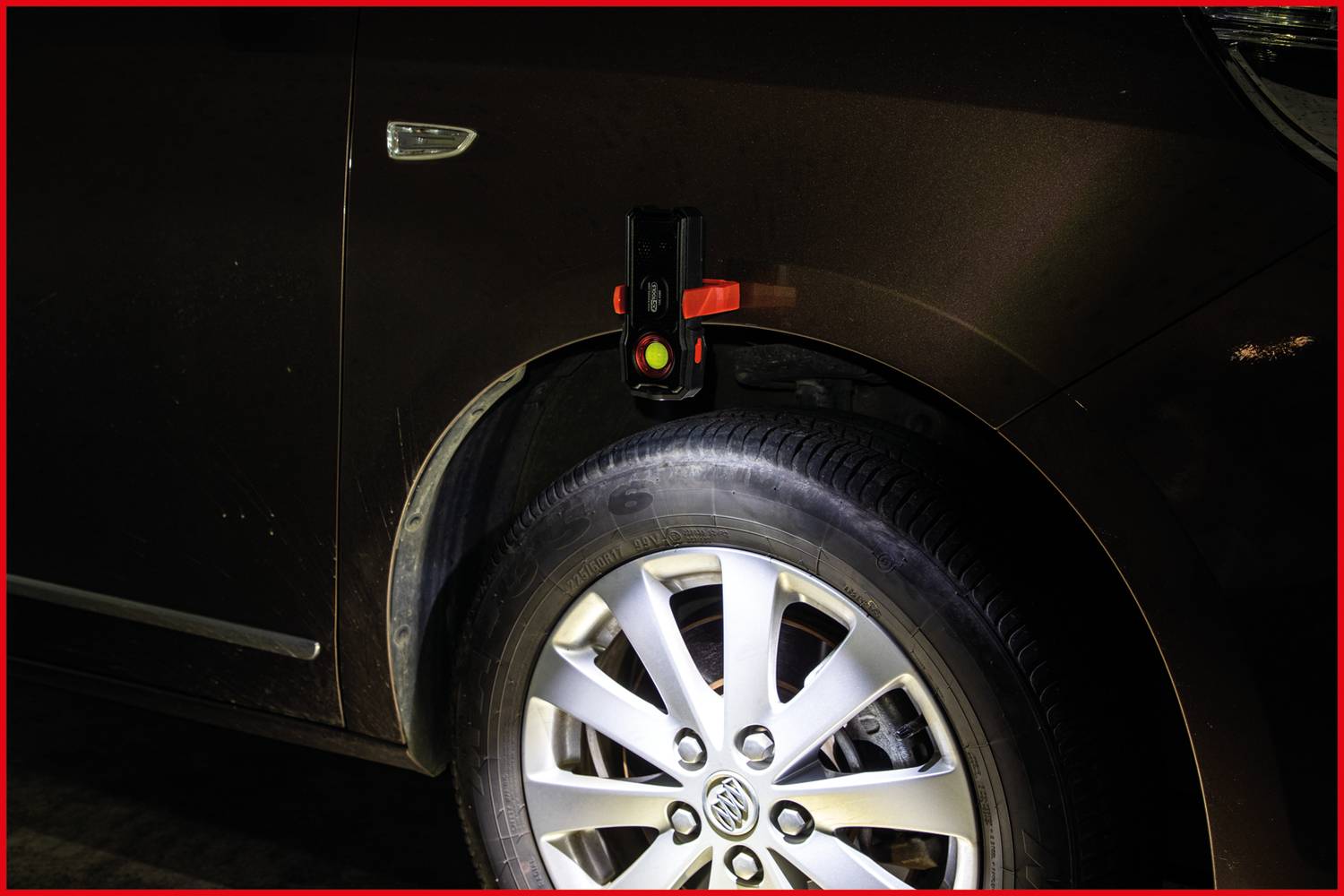 Nahaufnahme eines Autoreifens mit einem roten Licht an einem Gerät über dem Reifen montiert. Das Licht signalisiert eine Warnfunktion.