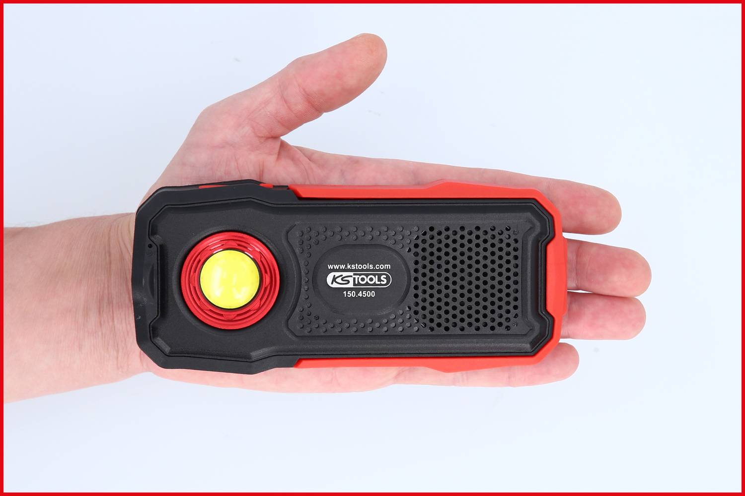 Eine Hand hält eine schwarze, rechteckige Taschenlampe mit rotem Rand und einem gelben Licht in der Mitte, auf der 'KS TOOLS' steht.