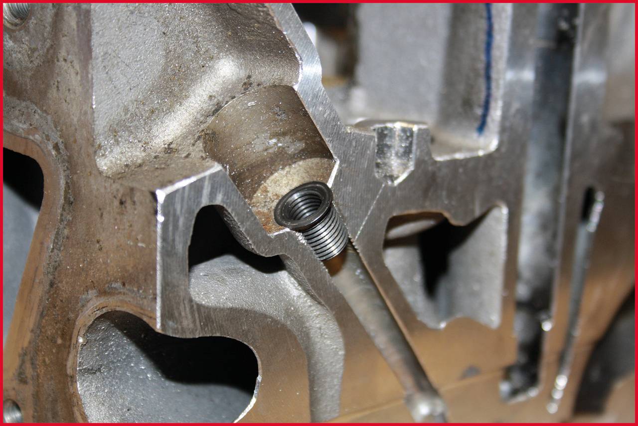 Nahaufnahme einer Metallfeder, die aus einer Öffnung in einem mechanischen Bauteil ragt. Hintergrund zeigt bearbeitetes Metall.
