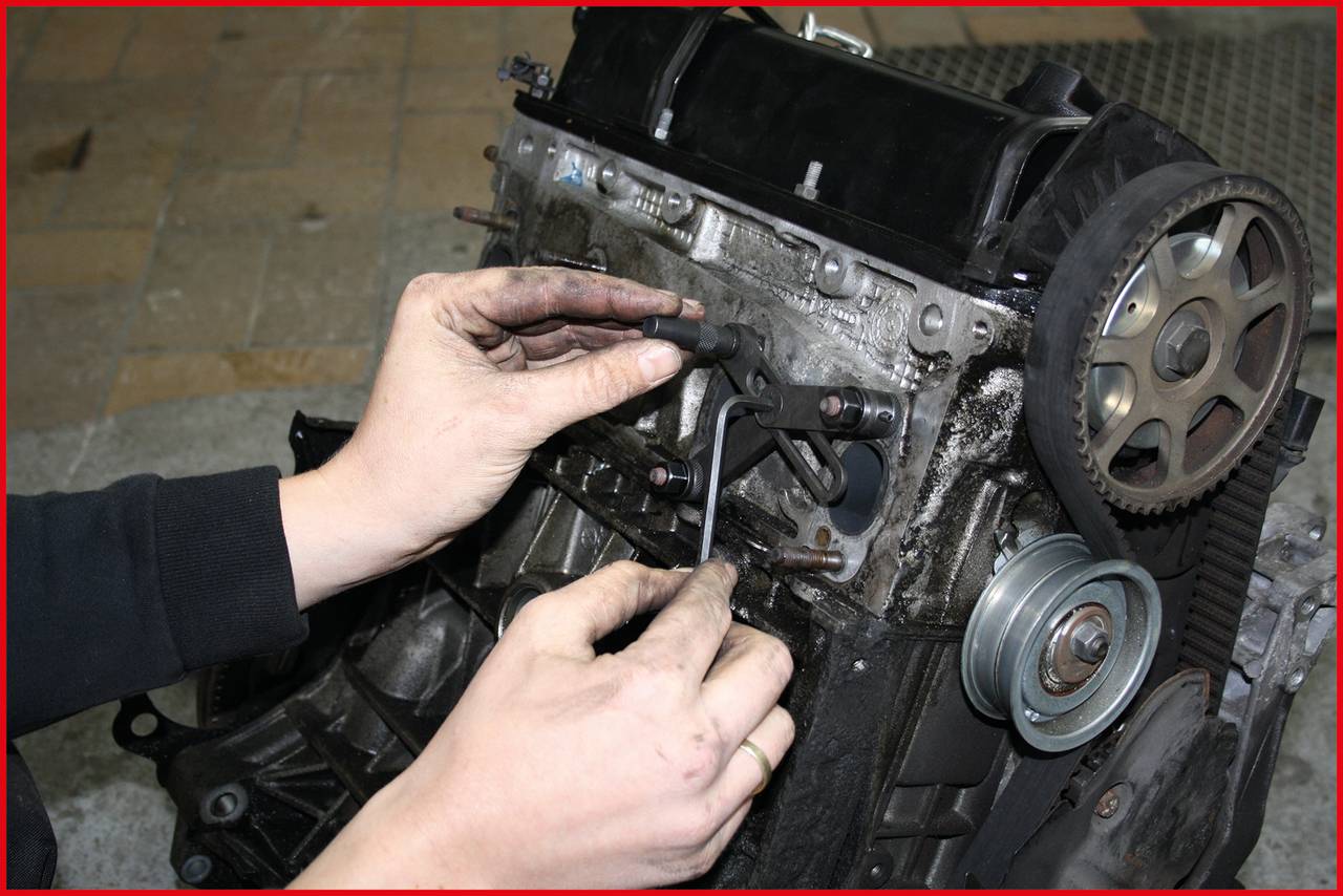 Eine Person repariert einen Motor mit einem Inbusschlüssel, umgeben von Motorbauteilen. Die Szene zeigt einen technischen Arbeitsvorgang.
