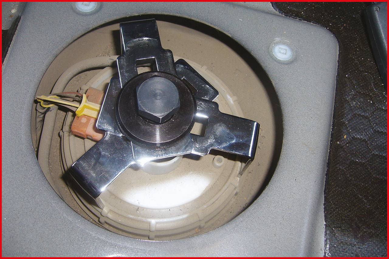 Metallkomponente in einem elektrischen Gerät, umgeben von Drähten und Kunststoffteilen; dient vermutlich zur Befestigung oder Verbindung.