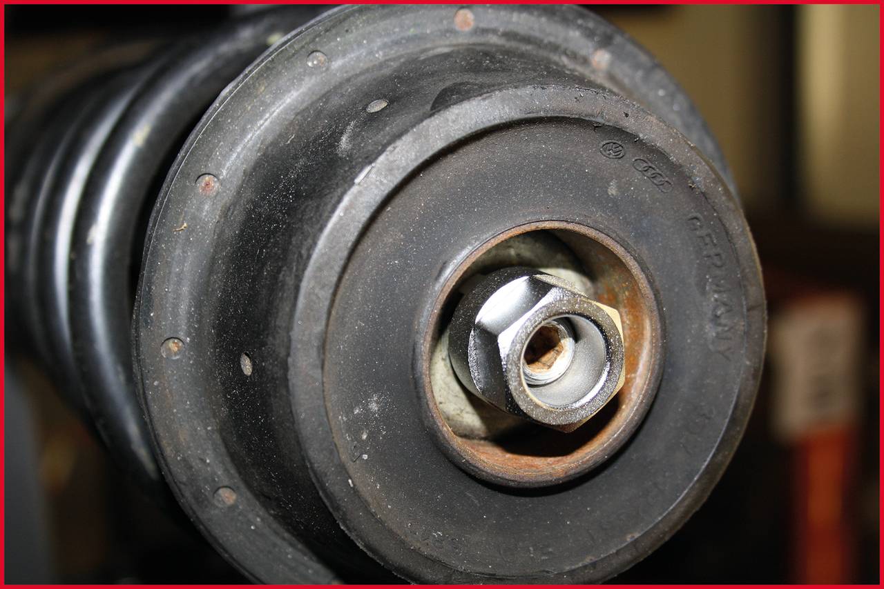 Nahaufnahme eines Autostoßdämpfers. Eine Mutter ist in der Mitte sichtbar, umgeben von Metall- und Gummiteilen.