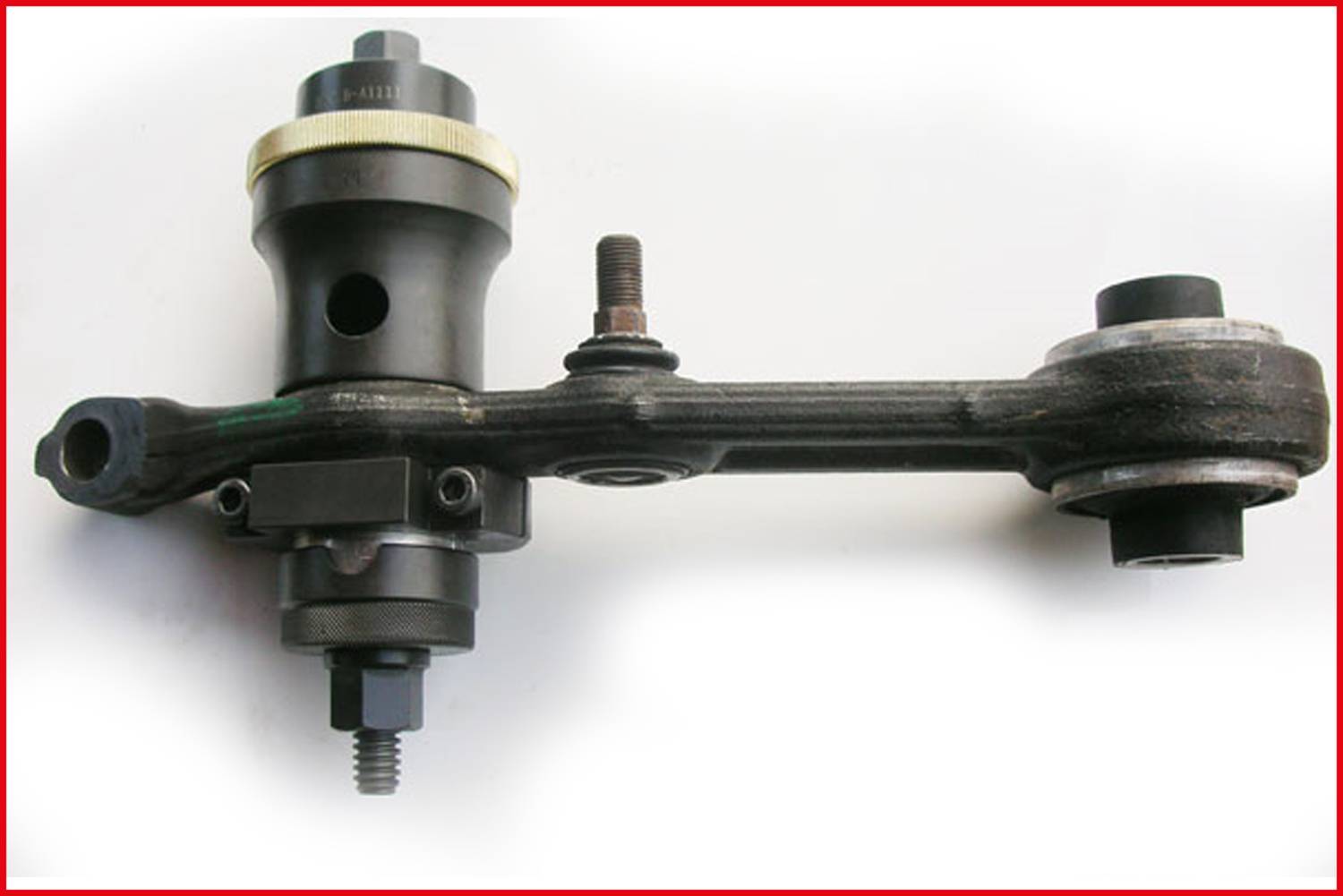 Ein schwarzes Metallteil mit mehreren Schrauben und einem zylindrischen Element, vermutlich ein Teil eines Maschinen- oder Fahrzeugsystems.