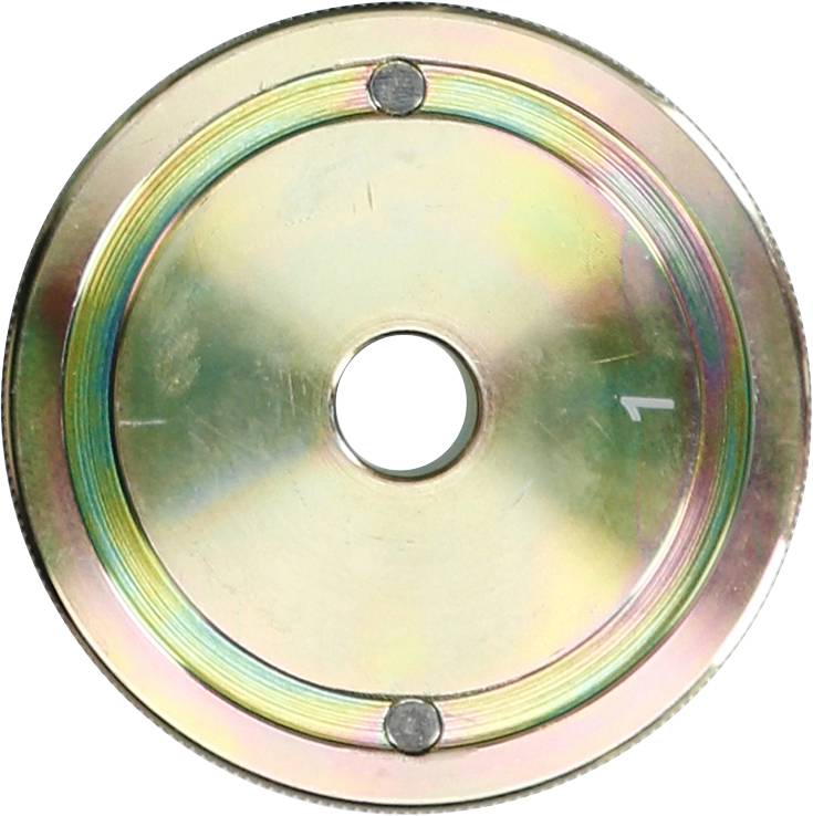 Rundes Metallobjekt mit zentralem Loch und drei gleichmäßig verteilten Einkerbungen am äußeren Rand. Schimmernde Oberfläche.