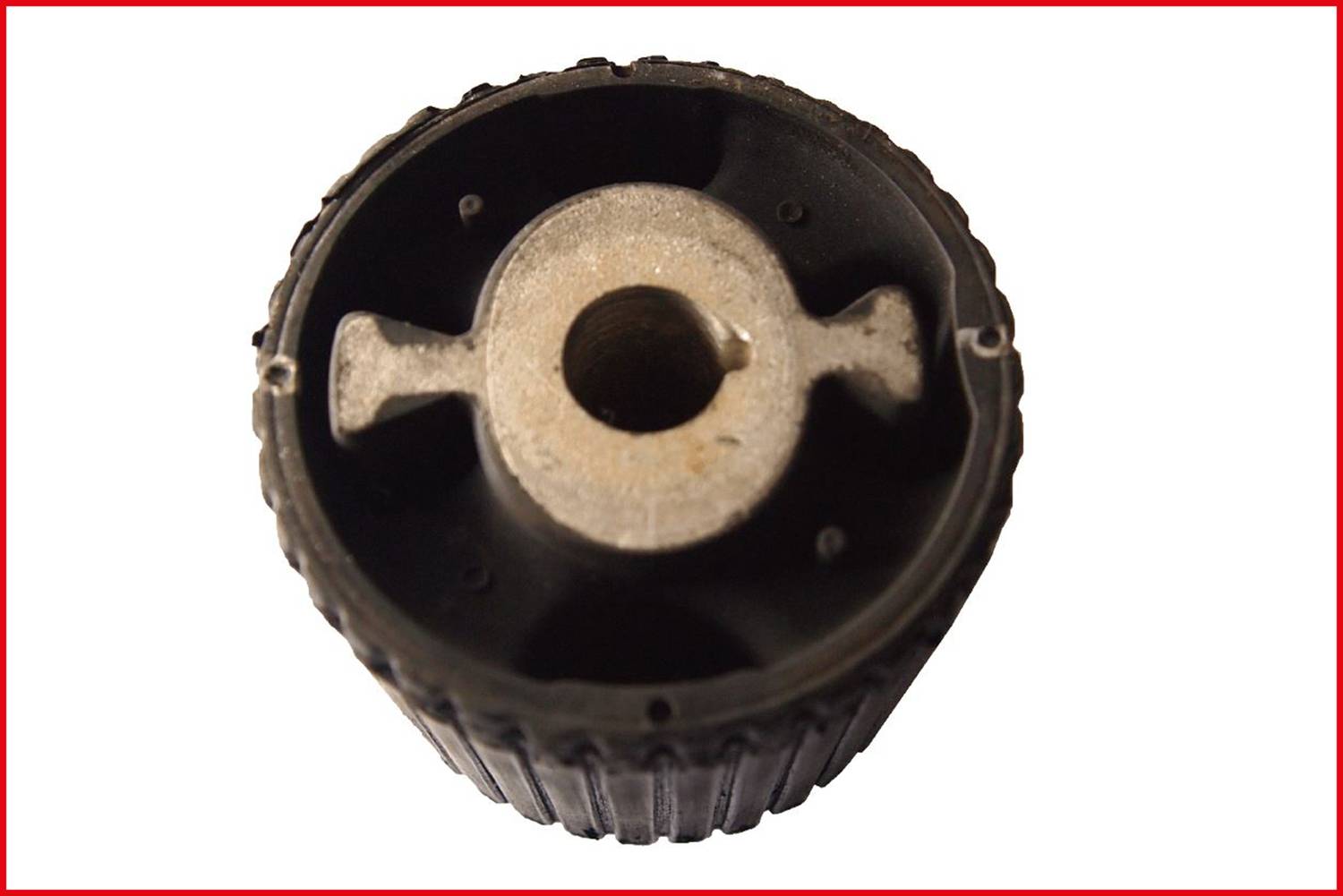 Ein schwarzes, geriffeltes Bauteil mit Metallkern, möglicherweise ein Zahnrad oder eine Rolle, von oben fotografiert.