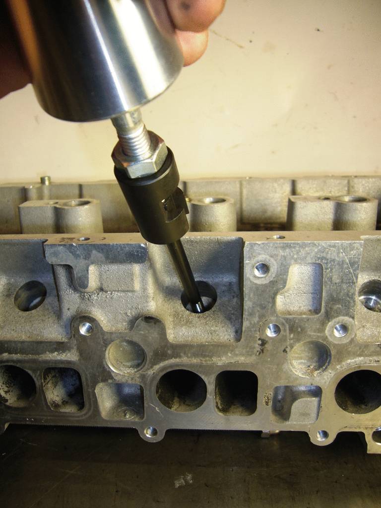 Eine Metallvorrichtung verwendet einen Werkzeugkopf, um ein Loch in einem grauen Motorblock zu bearbeiten.