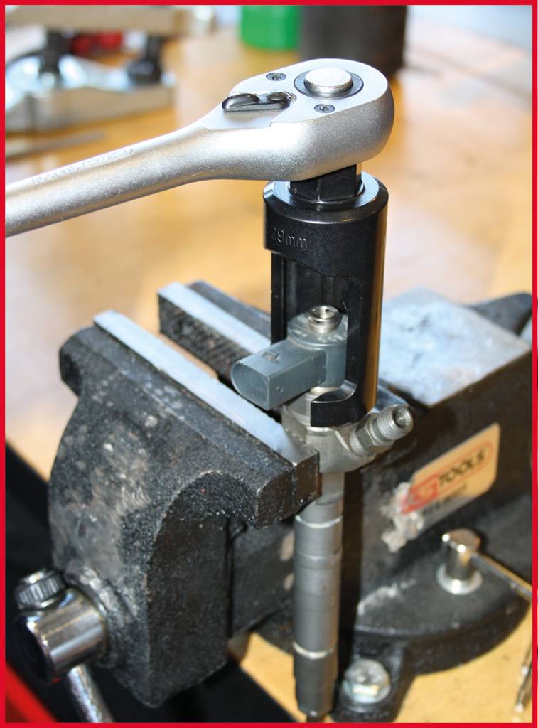 Ein Schraubstock hält ein Metallrohr, während ein Ratschenwerkzeug darauf angesetzt ist, um Arbeiten am Rohr durchzuführen.