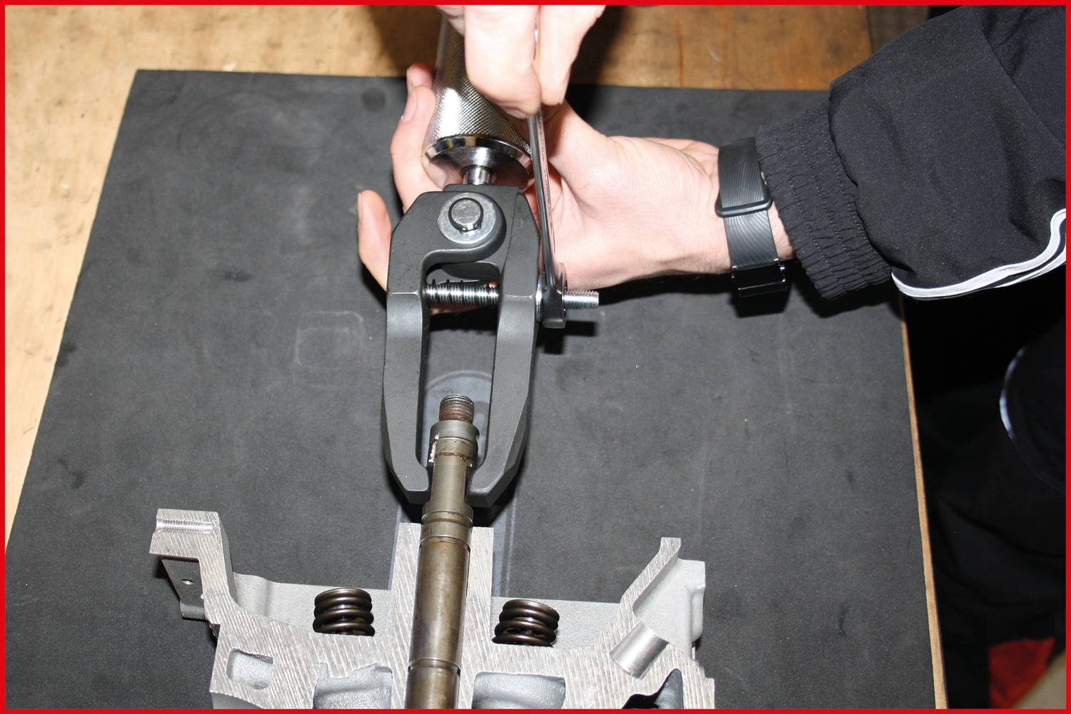 Hand zieht mit Werkzeug eine Schraube an einem mechanischen Bauteil an.