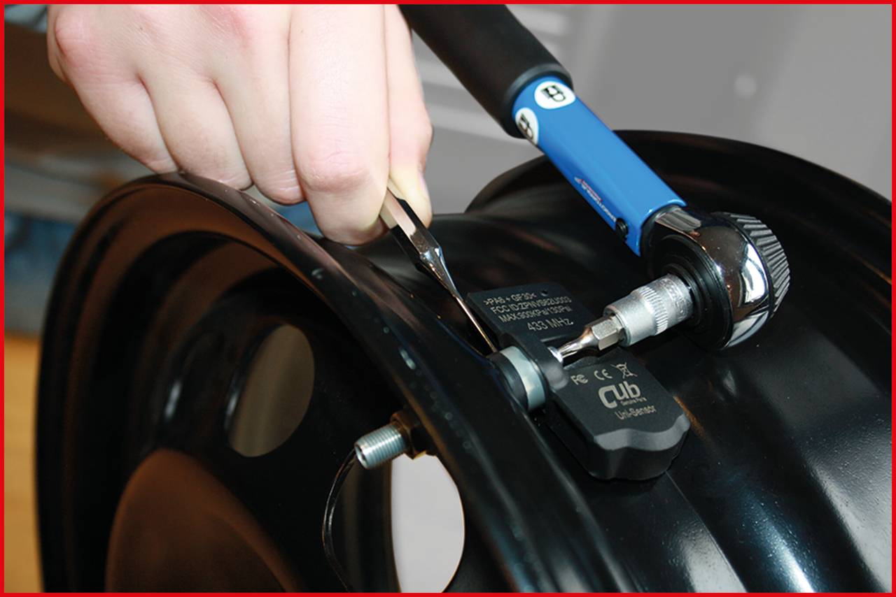 Hand montiert RDKS-Sensor an Felge mit Werkzeug; Detailaufnahme der Installation.