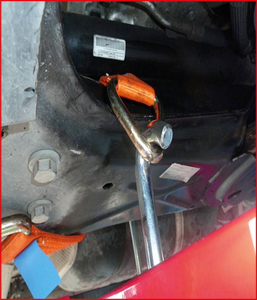 Ein Abschlepphaken ist an einem Auto befestigt. Ein orangefarbener Gurt ist ebenfalls sichtbar, der die Struktur sichert.