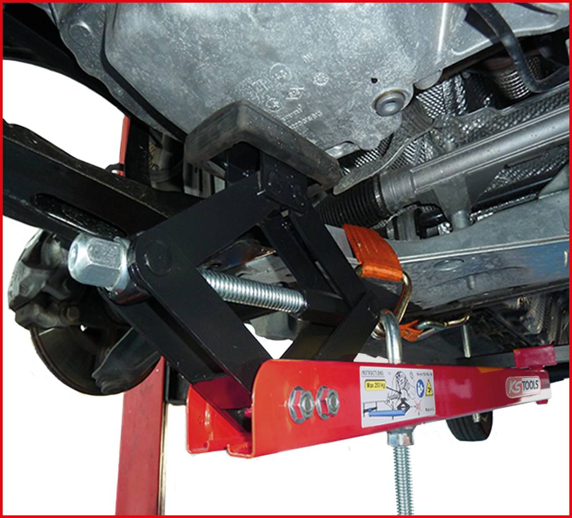 Ein Motorheber stützt einen Pkw-Motor im Kfz-Werkstattumfeld. Ein roter Metallrahmen und Schraubmechanismen sind sichtbar.