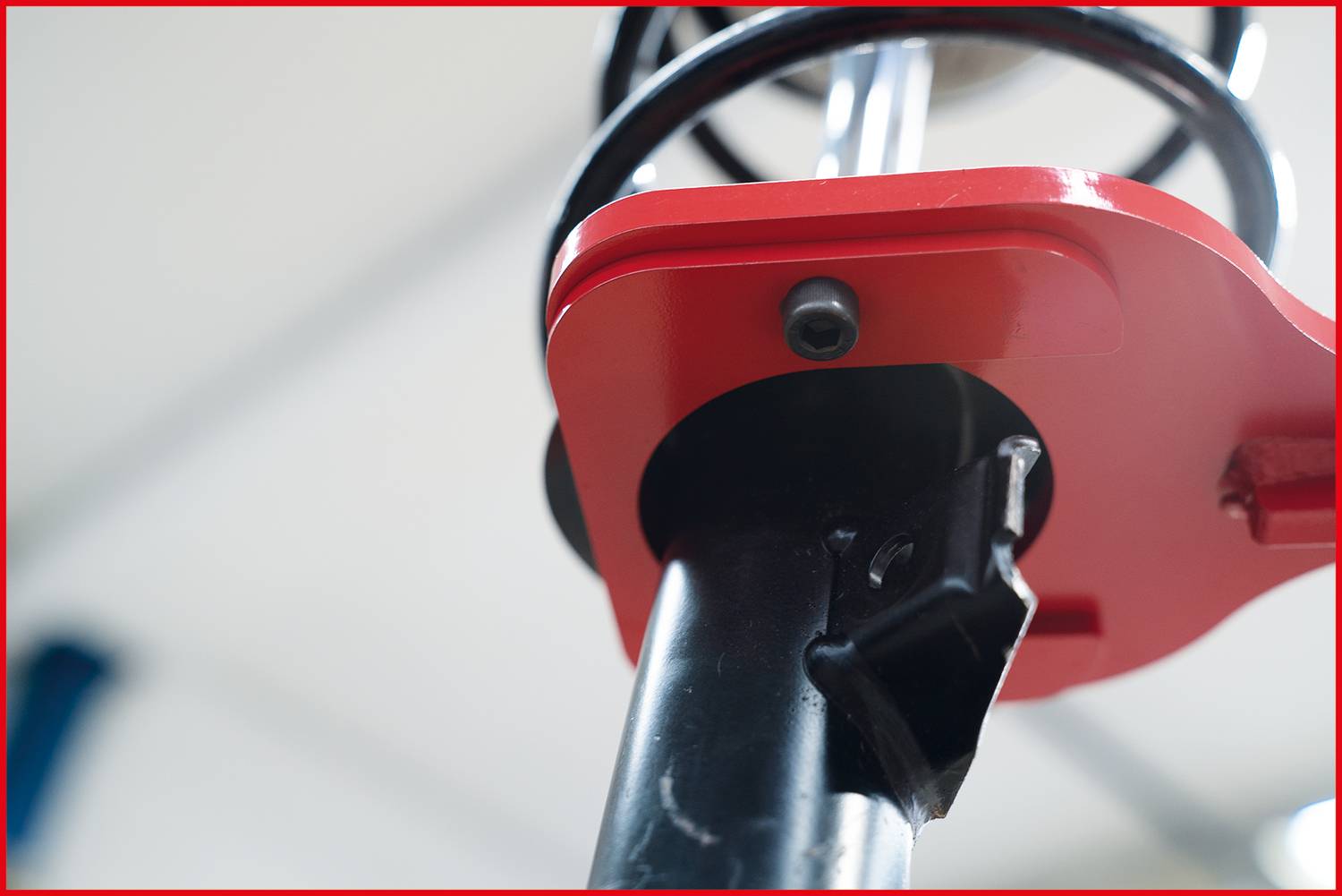 Nahaufnahme eines roten Metallteils an einer schwarzen Stange, möglicherweise Teil einer Maschine oder eines Geräts.