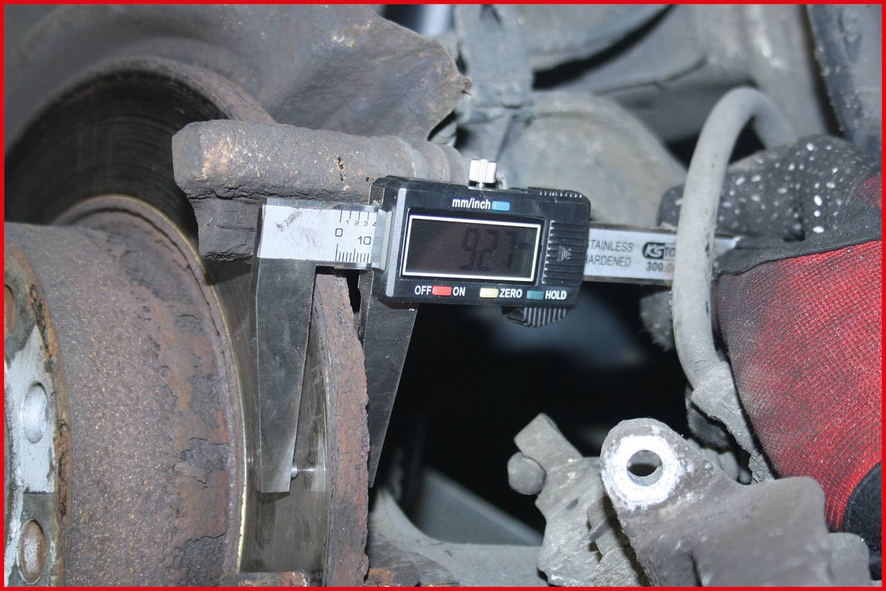 Ein Messschieber misst die Dicke einer Bremsscheibe, die Anzeige zeigt 9,27 mm. Die Scheibe ist Teil eines Autobremsensystems.