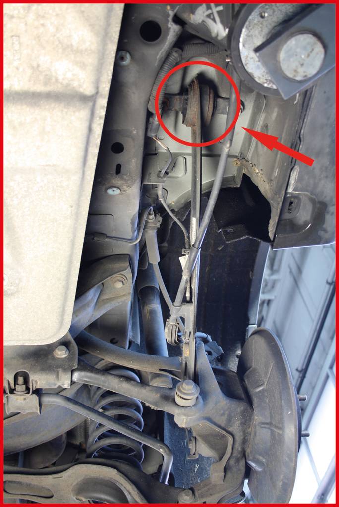 Bild eines Auto-Unterbodens, der einen beschädigten oder fehlenden Automobilpuffer zeigt, mit einem roten Kreis und Pfeil markiert.