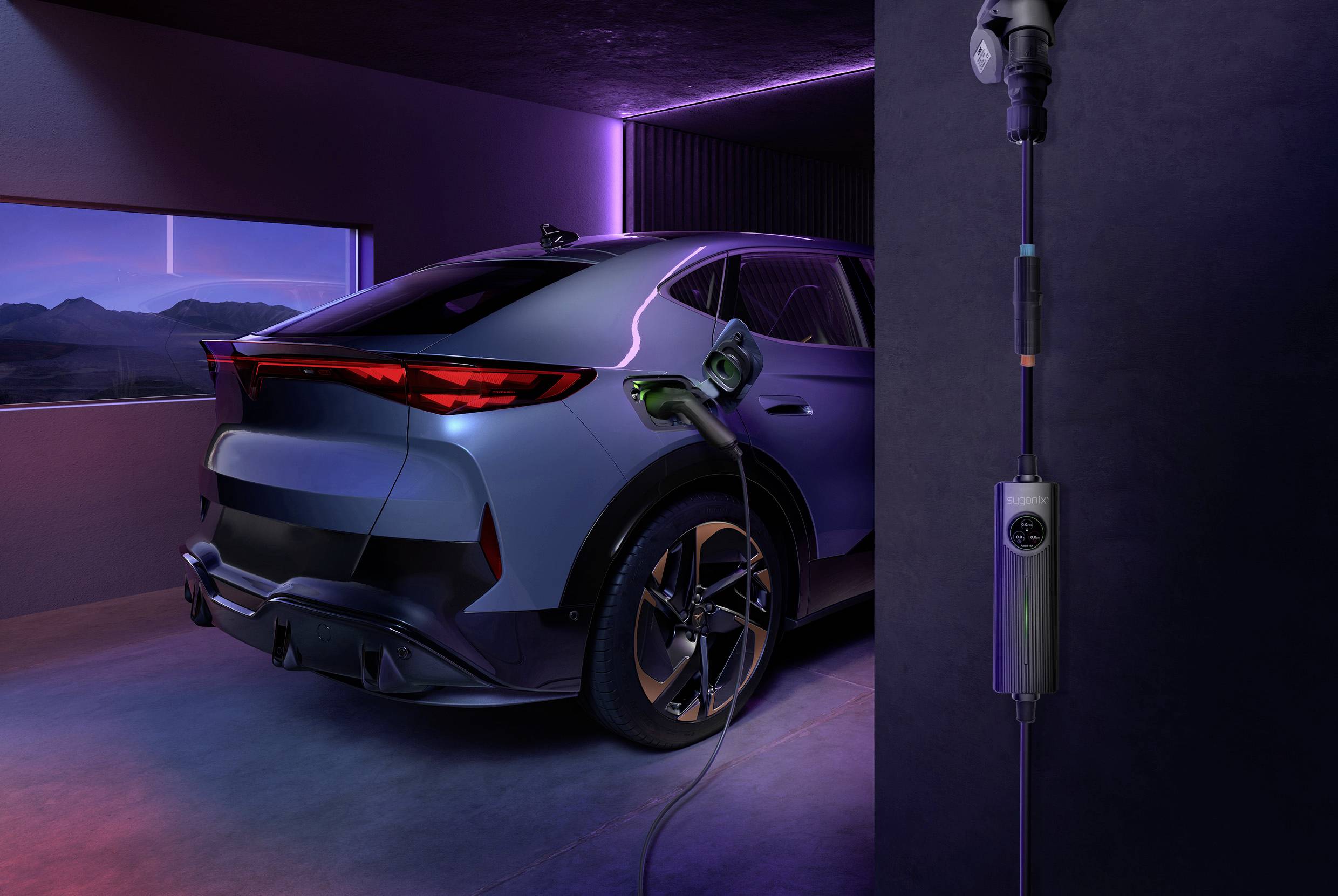Ein silbernes Elektroauto lädt in einer modernen Garage. Im Hintergrund sind Berge im Abendlicht durch ein Fenster zu sehen.