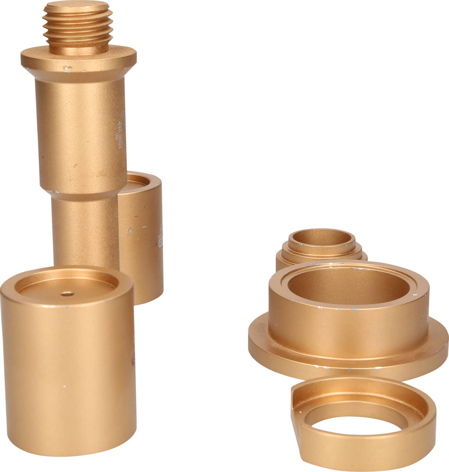 Zwei goldfarbene Metallteile, die aus mehreren Zylindern und Ringen bestehen, nebeneinander auf weißem Hintergrund.