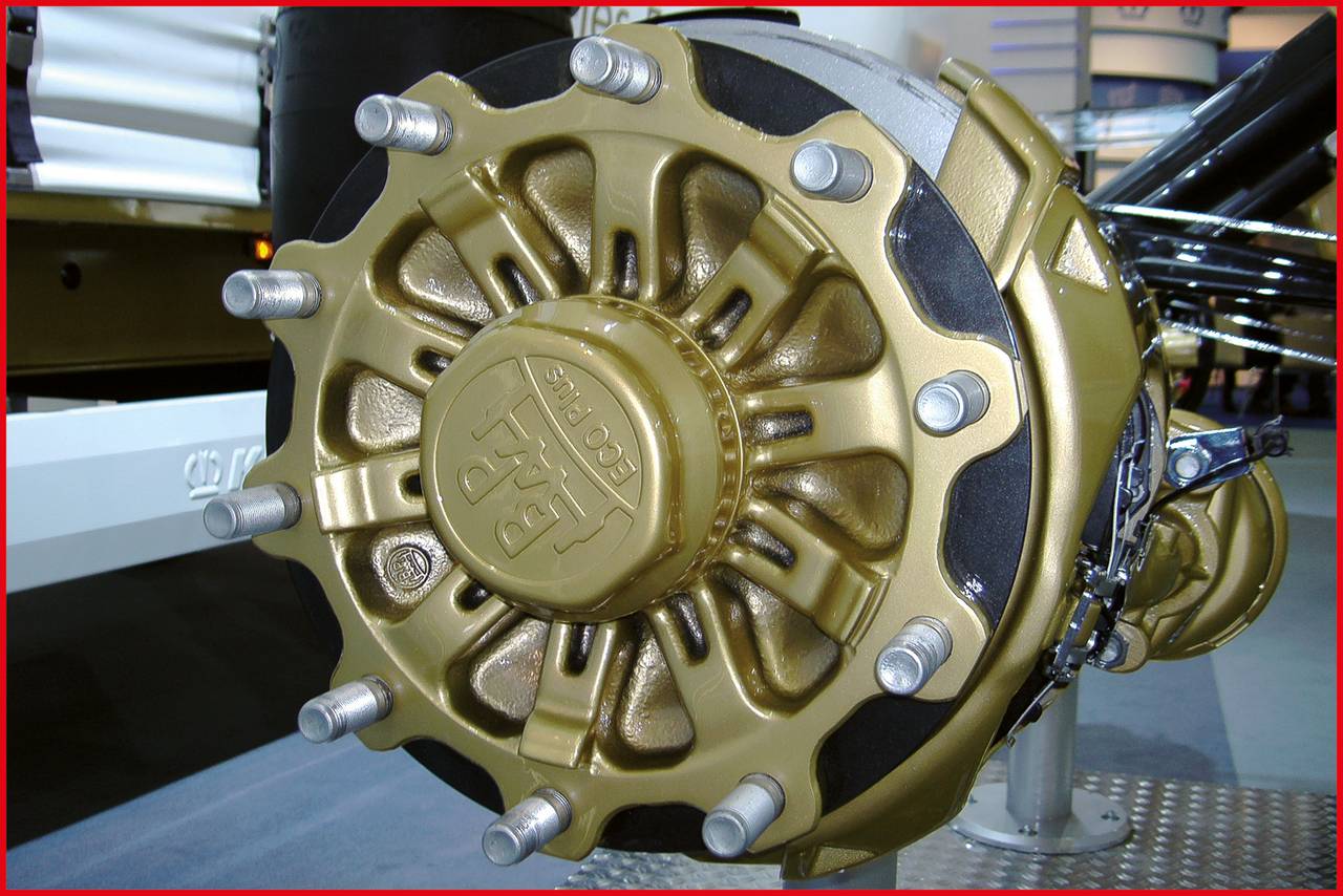 Nahaufnahme eines goldenen LKW-Radnabenmoduls mit acht Schrauben, montiert auf einer Achse in einer industriellen Umgebung.