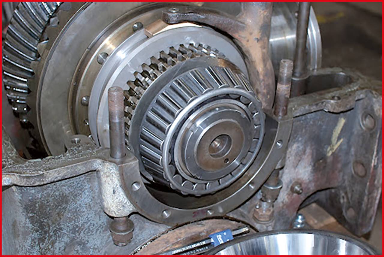Industrielle Maschine mit einem großen, metallischen Zahnrad im Zentrum, umgeben von robusten Halterungen.