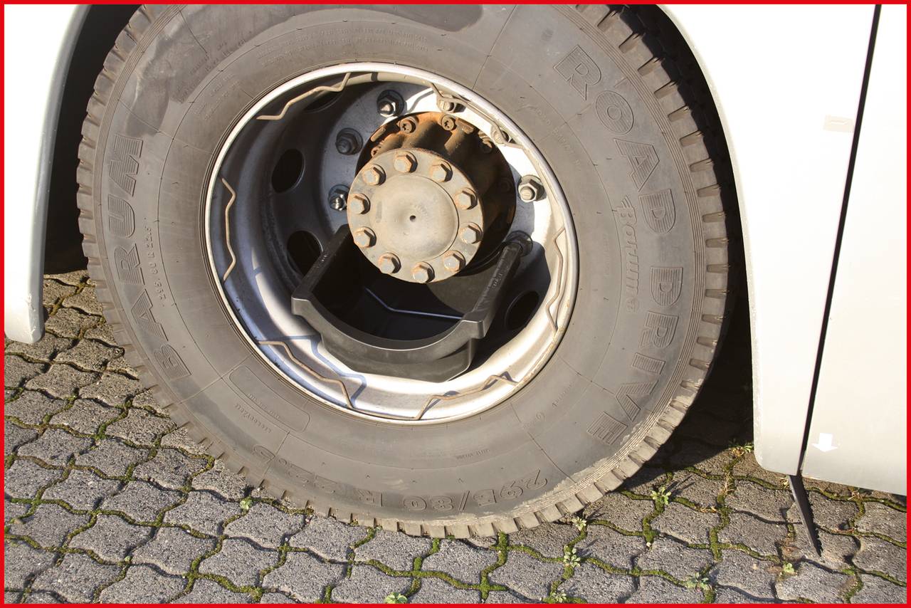Ein Busreifen ist von nahem zu sehen. Er steht auf einem gepflasterten Boden. Der Radbolzen und die Felge sind sichtbar.