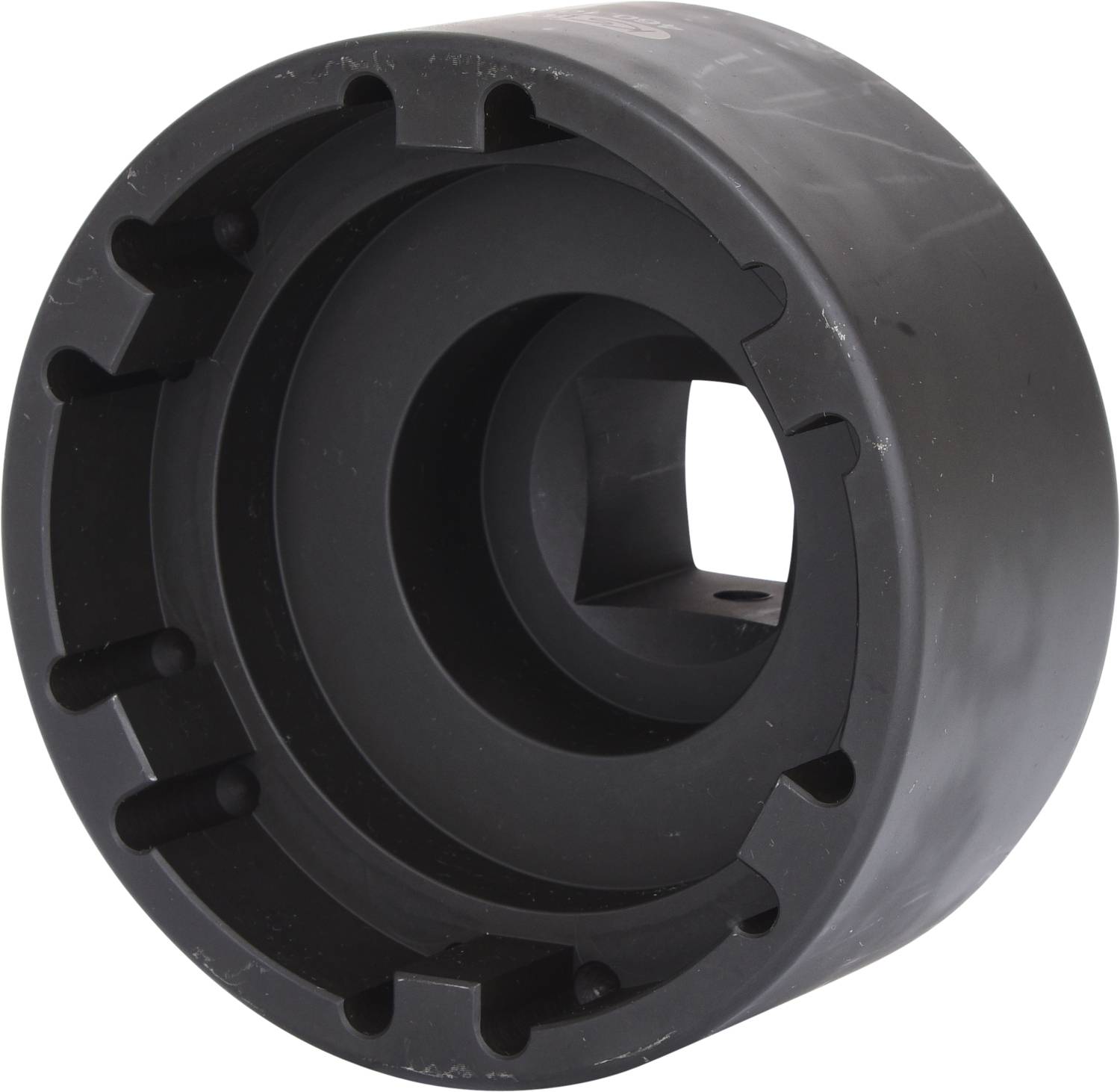 Schwarzes, kreisförmiges Kunststoffteil mit konzentrischen Ringen und rechteckigem Innenausschnitt, möglicherweise ein Maschinenelement.