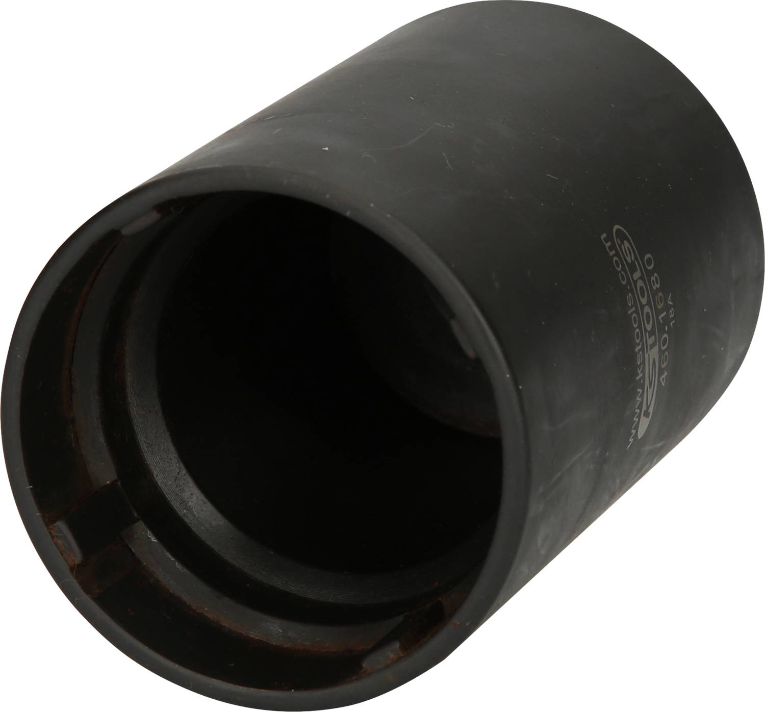 Eine schwarze, zylindrische Hülse aus Metall mit einer geöffneten Seite und eingeprägten Markierungen an der Außenseite.
