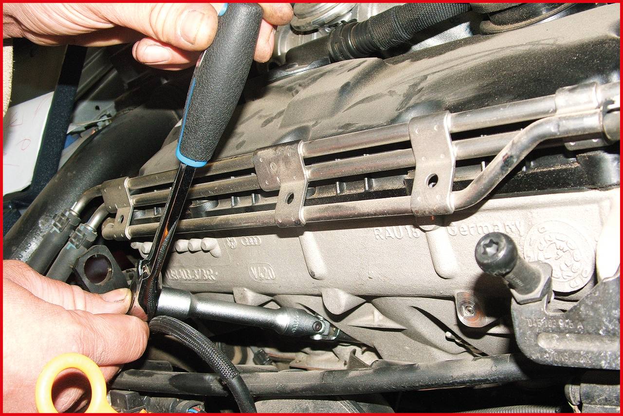 Mensch schraubt mit Schraubendreher an Motorblock.