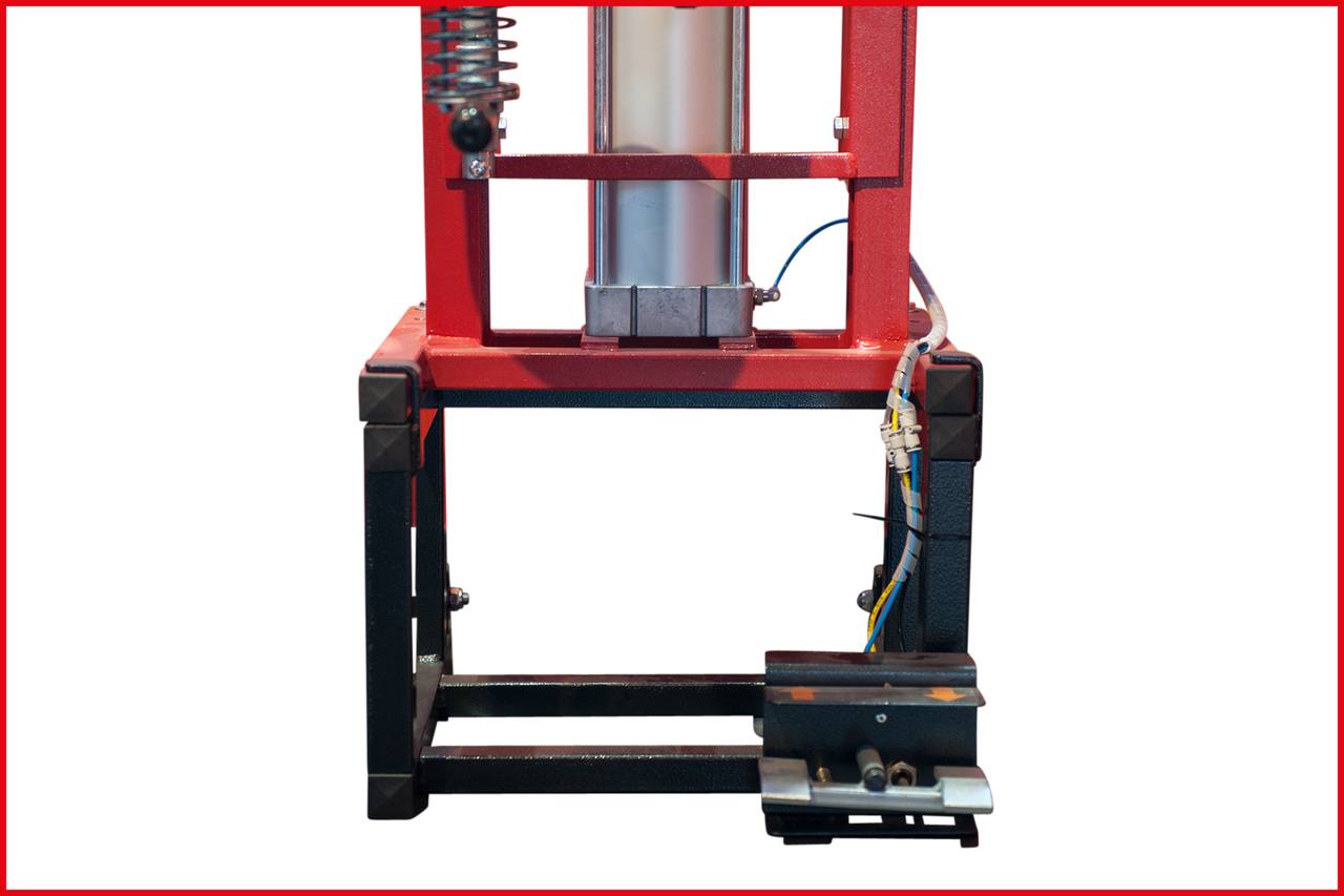 Maschine mit rotem Rahmen und silbernem Zylinder, auf schwarzem Gestell montiert. Kabel und Federn sichtbar. Funktion unklar.