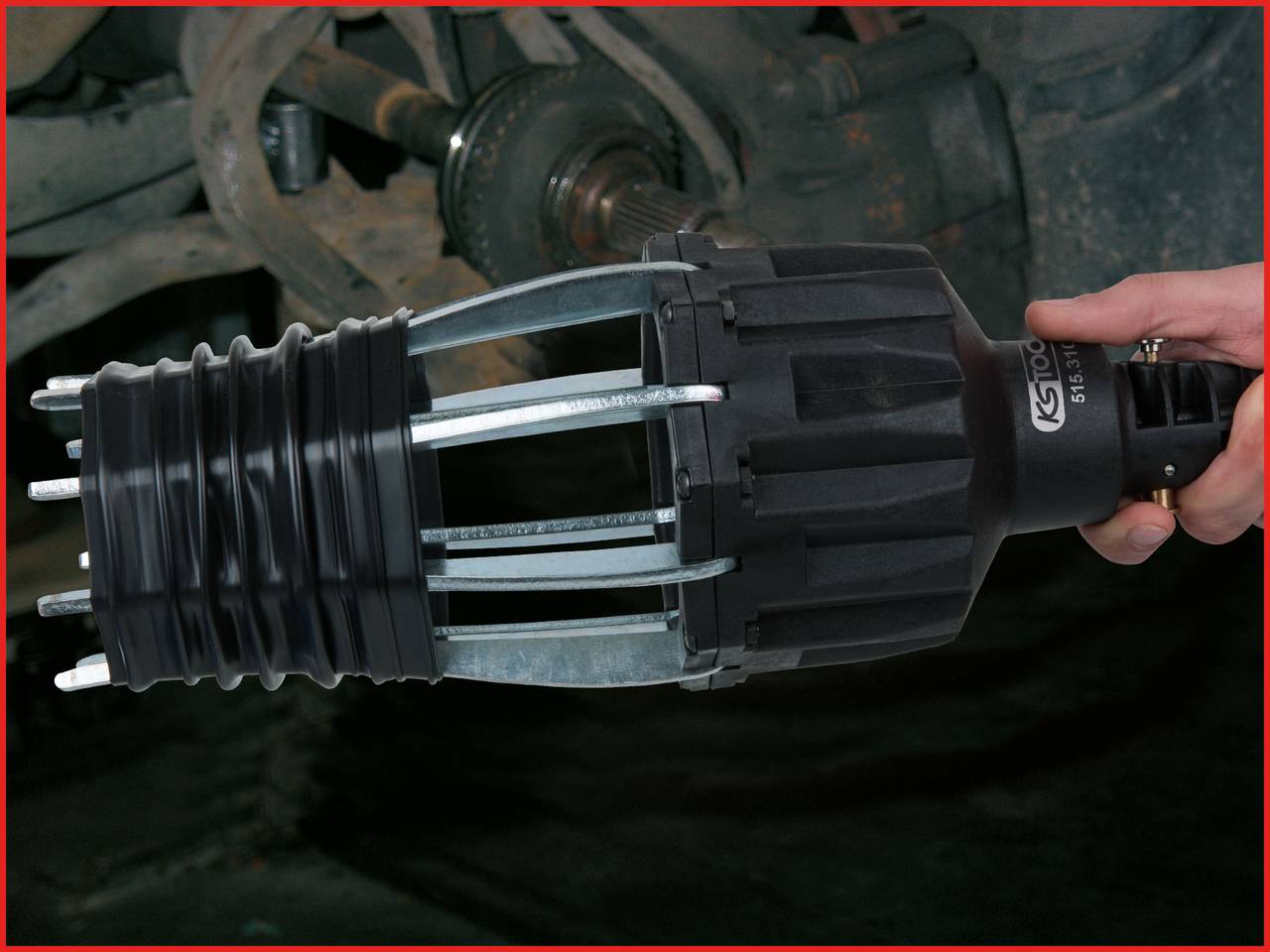 Eine Hand hält ein Werkzeug zum Entfernen einer Radmutter, das auf eine Achse aufgezogen ist. Reparaturszene in einer Werkstatt.