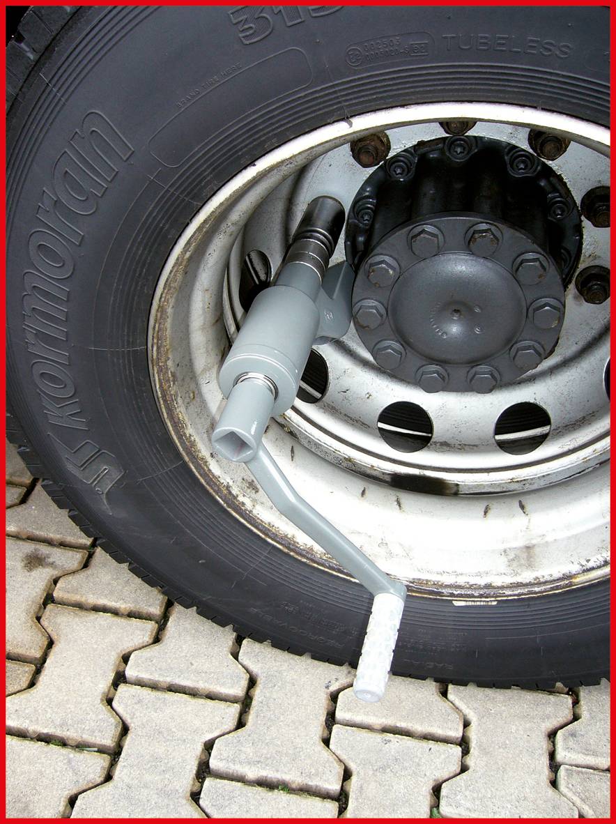 LKW-Reifen mit montiertem Drehmomentschlüssel auf Pflastersteinen. Drehmomentschlüssel dient zum Prüfen oder Festziehen von Radmuttern.