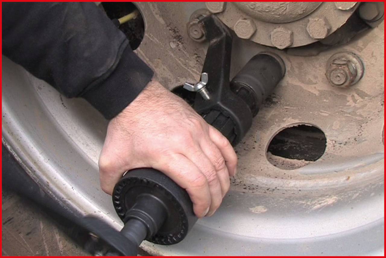 Eine Person benutzt ein Werkzeug, um eine Radmutter auf einer Radfelge zu lösen oder anzuziehen.