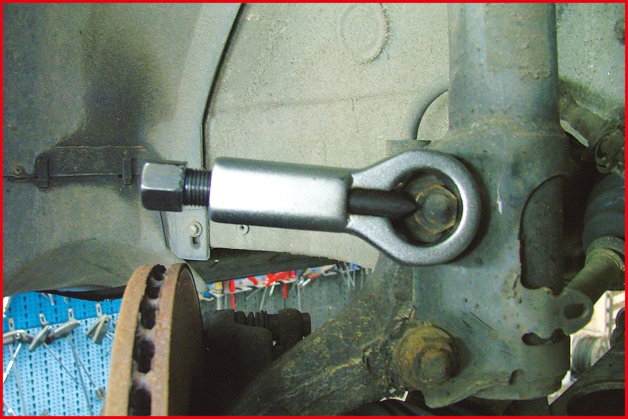 'Umlenkhebel' in einem Auto, der an einer Metallhalterung befestigt ist. Daneben eine Bremsscheibe und sichtbare Mechanikteile.