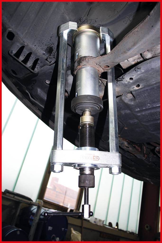 Ein Stoßdämpfer wird an der Unterseite eines Fahrzeugs montiert. Das Werkzeug ist befestigt und wird zur Installation verwendet.