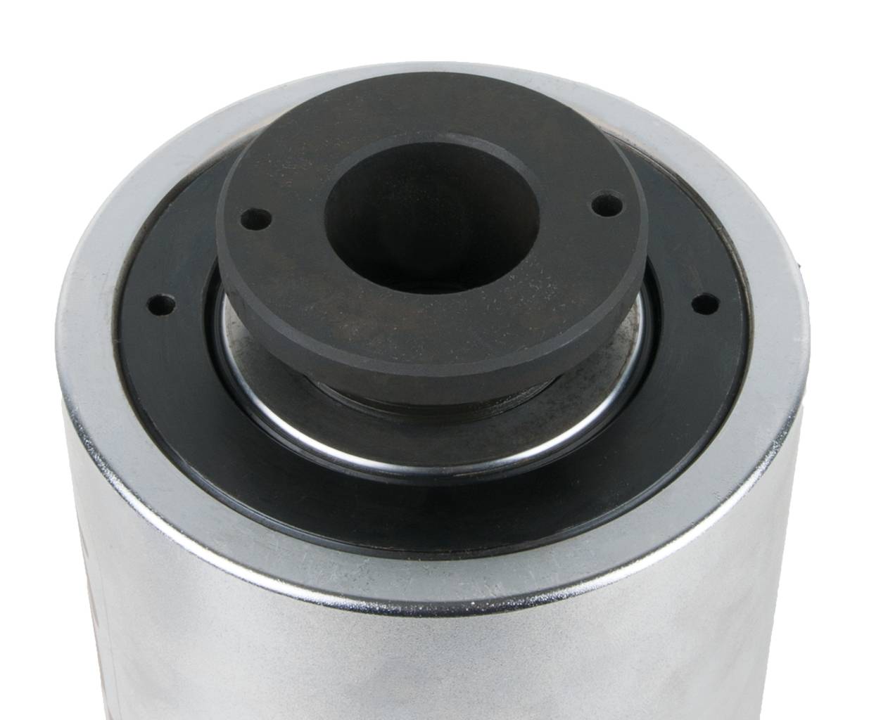Ein zylindrisches Metallteil mit schwarzer Öffnung und Löchern oben. Teil einer Maschinenkomponente.