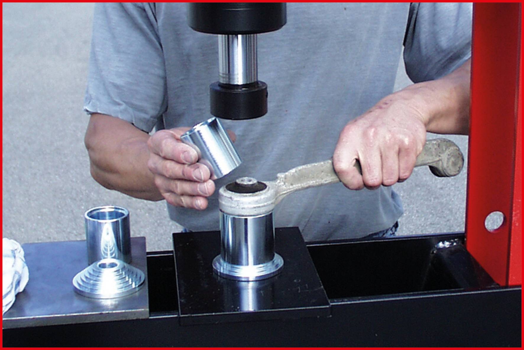 Mann verwendet eine Presse, um ein Metallteil zu formen. Ein Werkstück wird in die Presse geschoben, während ein anderes danebenliegt.