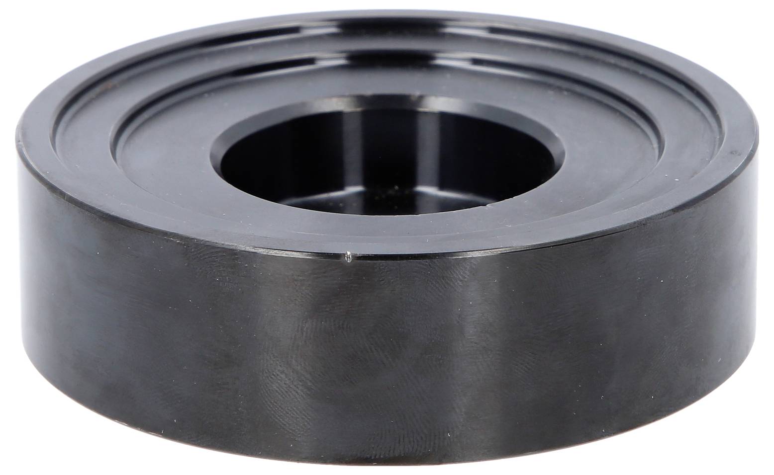 Schwarzes zylindrisches Metallgleitlager oder Rollenlager mit zentralem Loch, dargestellt vor weißem Hintergrund.
